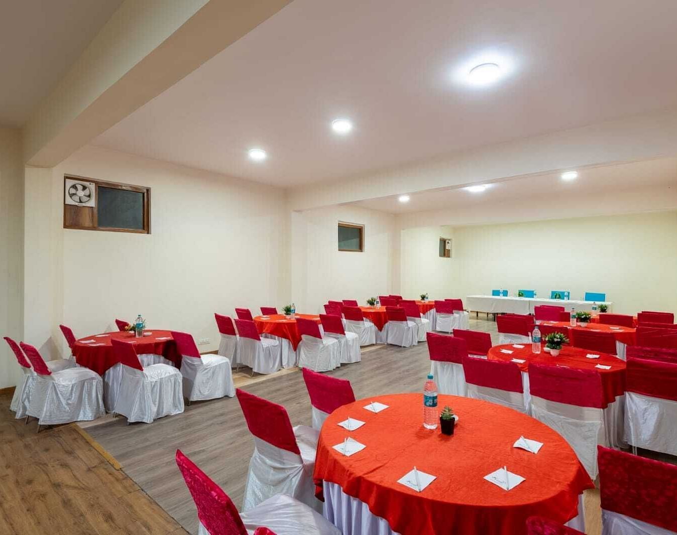 Image of a banquet hall with round tables and red chairs  | DLS Serenity Resort and Spa